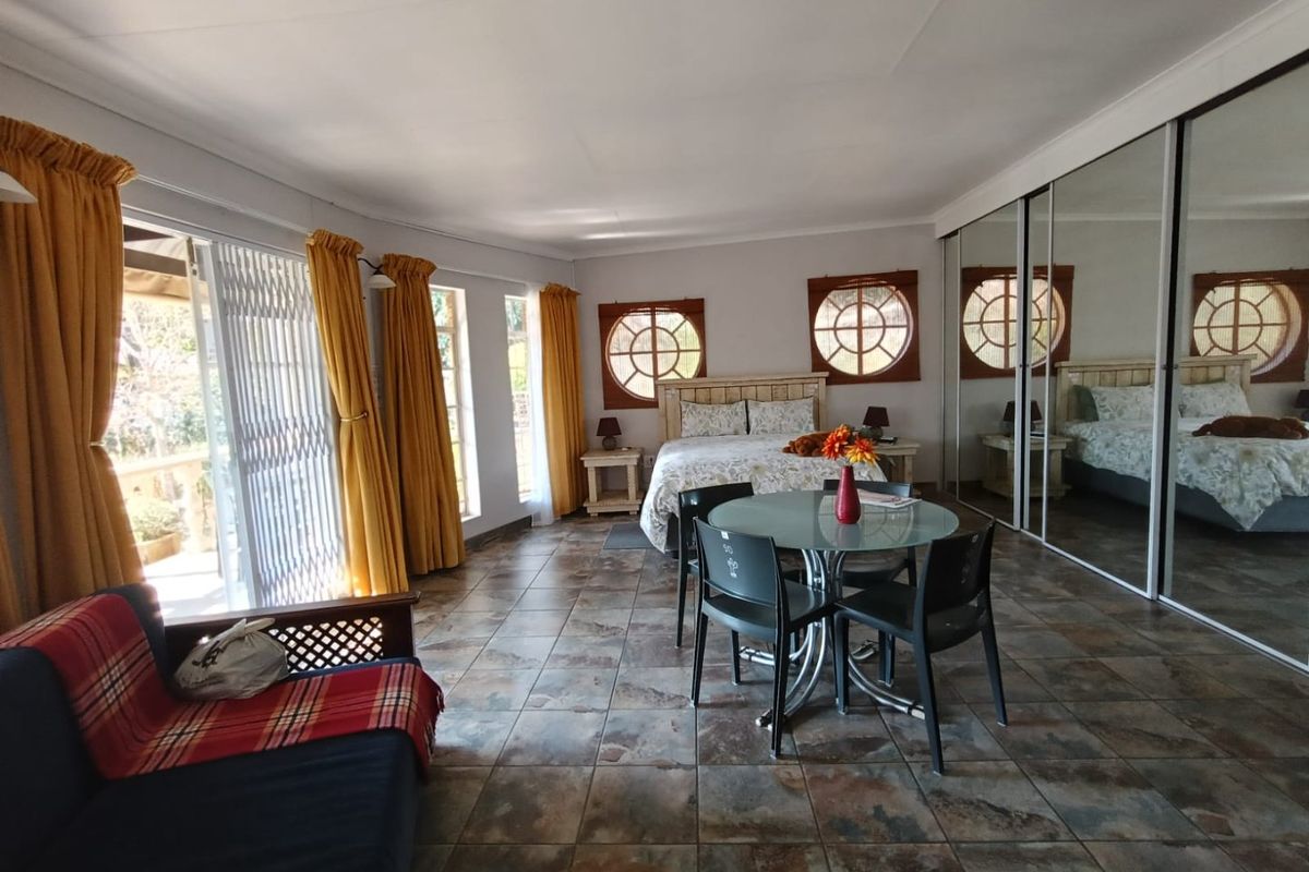 Spacious bedroom featuring tiled flooring, mirrored built-in cupboards, unique circular windows, and direct access to an outdoor area through sliding glass doors.