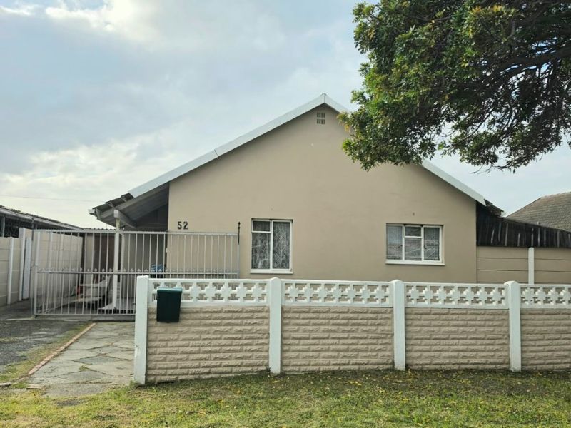 Front elevation of a residential apartment featuring a paved driveway, secure metal gate, and a precast concrete boundary wall.