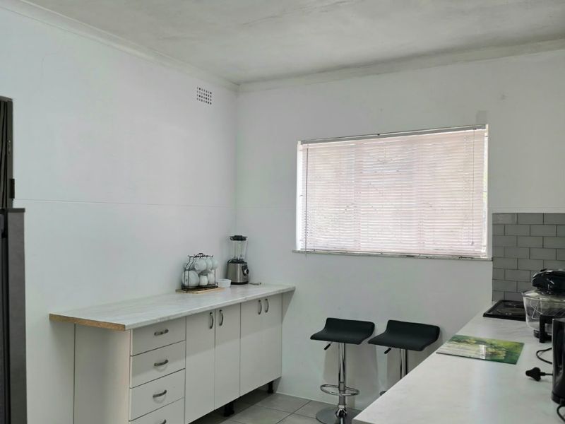 A functional kitchen featuring white cabinetry, laminate countertops, subway tile backsplash, and tiled flooring, providing a clean and practical workspace.