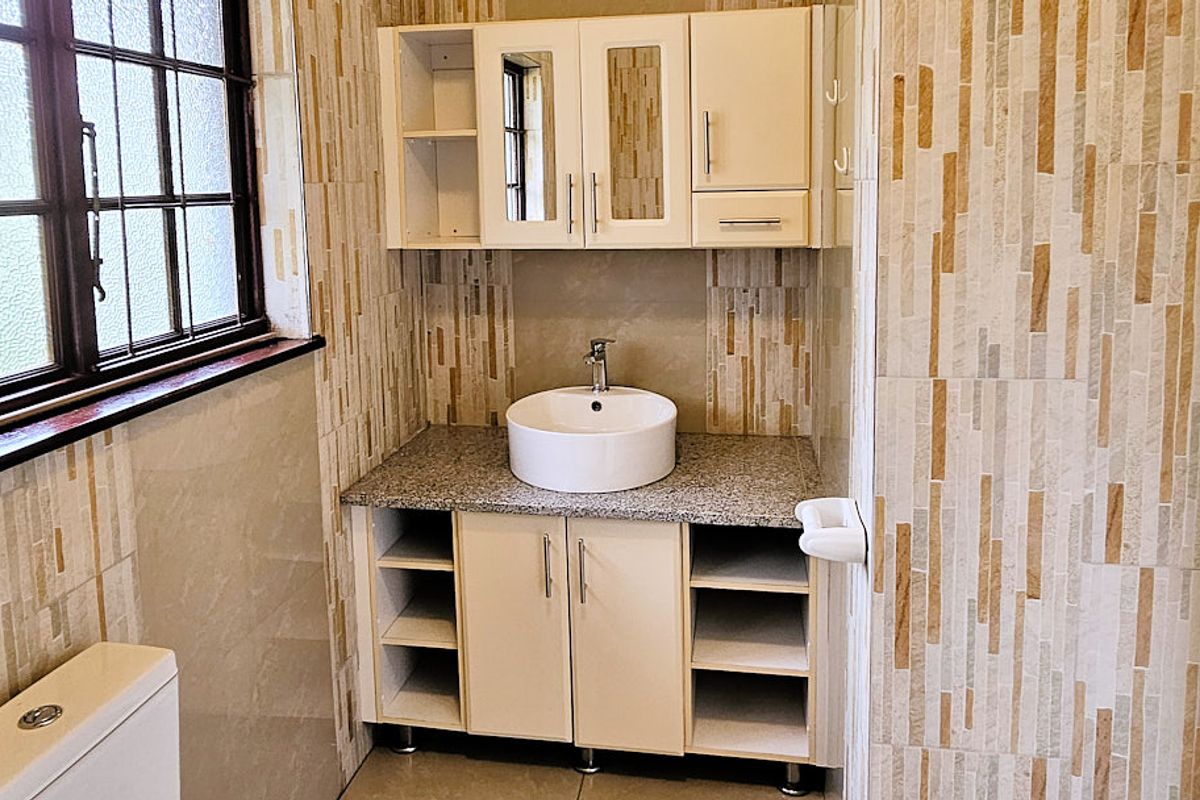 A clean bathroom featuring a vessel sink on a granite vanity, wall-mounted storage cabinets, and decorative tiled wall finishes.