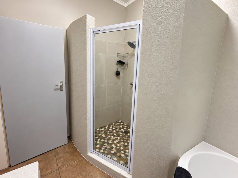 A functional bathroom featuring a tiled shower enclosure with a glass door and a built-in bathtub.