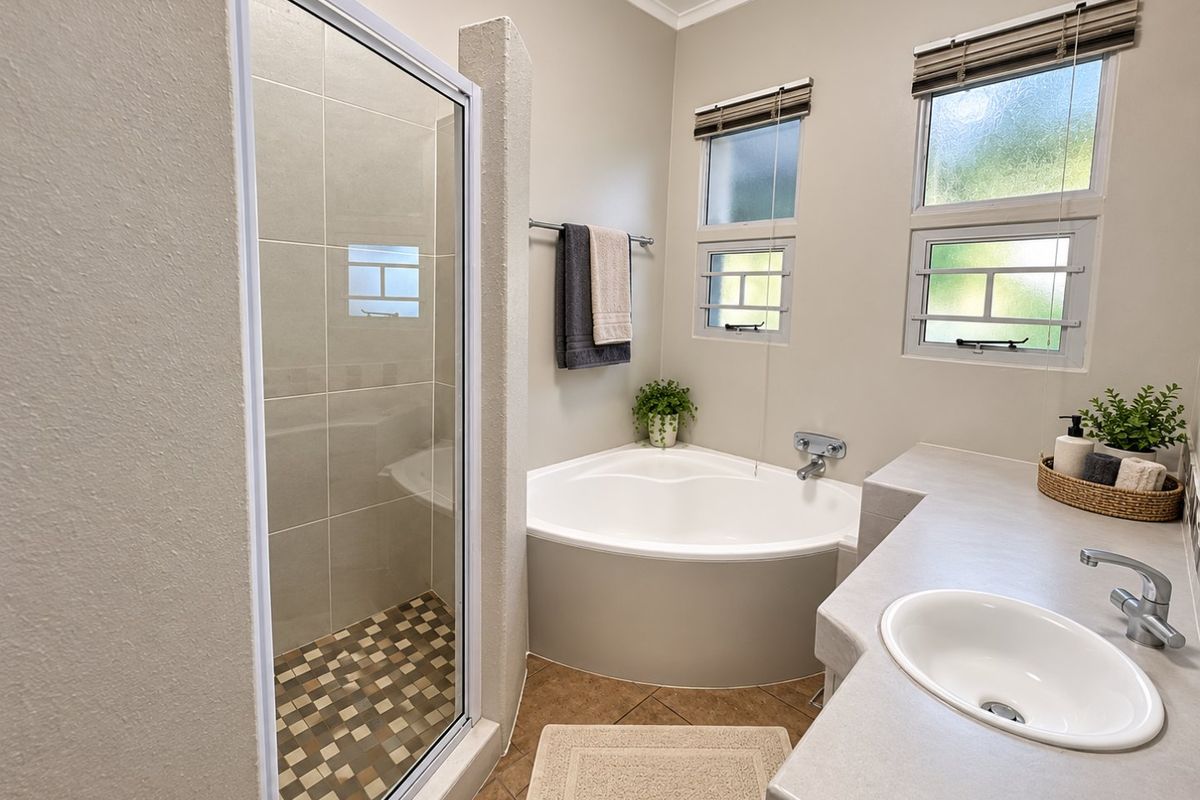 A well-maintained bathroom featuring a corner bathtub, a separate shower enclosure with tiled flooring, and a vanity with an inset sink.