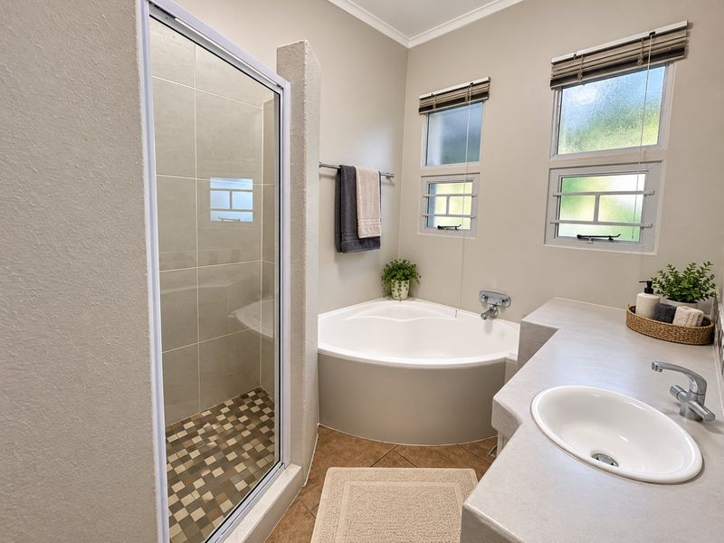 A well-maintained bathroom featuring a corner bathtub, a separate shower enclosure with tiled flooring, and a vanity with an inset sink.
