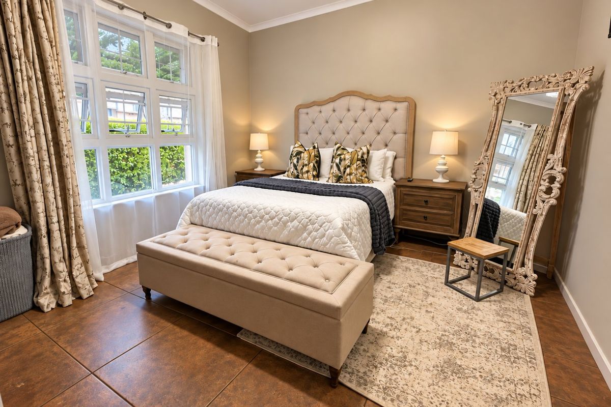 A well-maintained bedroom featuring large multi-pane windows, neutral wall tones, and durable tiled flooring, creating a bright and comfortable living space.