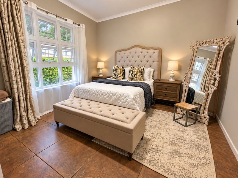 A well-maintained bedroom featuring large multi-pane windows, neutral wall tones, and durable tiled flooring, creating a bright and comfortable living space.