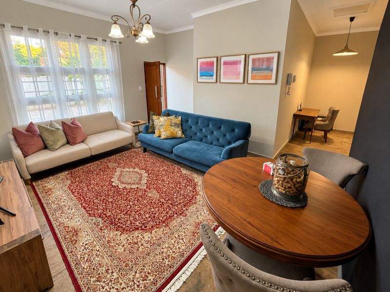A bright and spacious open-plan living and dining area featuring neutral walls, tiled flooring, and elegant lighting fixtures.