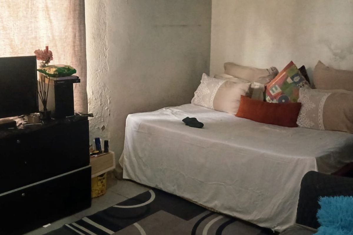 A bedroom featuring visible wall surface deterioration and peeling paint, requiring cosmetic attention to improve the overall condition of the space.