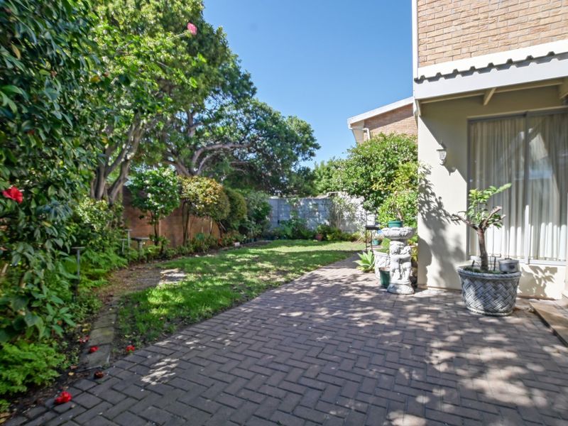 A private rear garden featuring a brick-paved patio area, established lawn, and mature perimeter landscaping, providing a peaceful outdoor space.