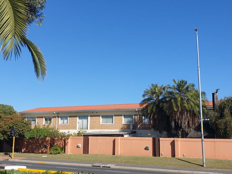 Front exterior view of the Mardri Hof apartment complex, featuring a brick facade, tiled roof, and secure perimeter wall.