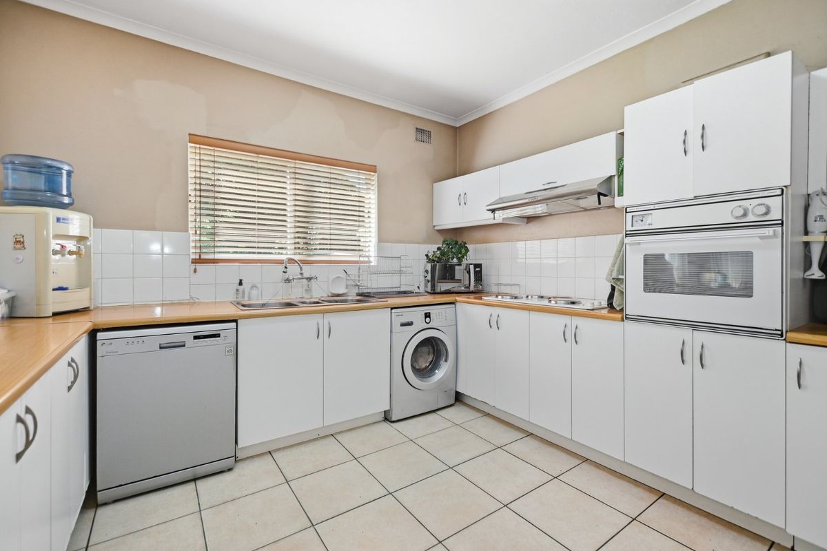A functional kitchen featuring white cabinetry, laminate countertops, built-in oven, and tiled flooring, requiring cosmetic updates to the wall finishes.