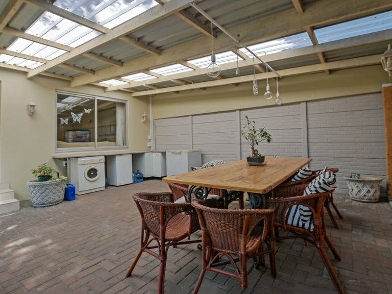 Covered outdoor patio area featuring a translucent roof, brick paving, and a built-in counter space, ideal for alfresco dining and entertaining.