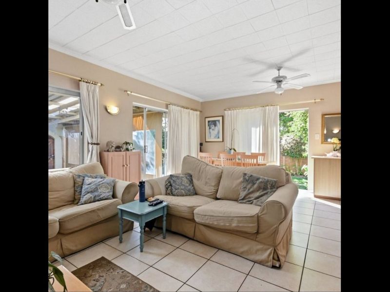 Open plan living and dining area featuring tiled flooring, ceiling fans, and multiple sliding glass doors providing access to the outdoor space.