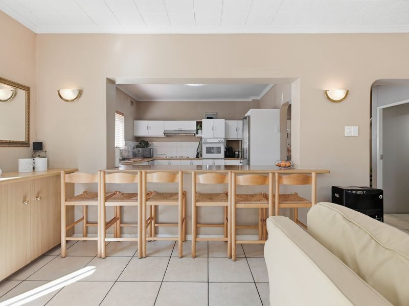 Open plan living area featuring a breakfast bar connecting to the kitchen, tiled flooring, and neutral wall finishes.