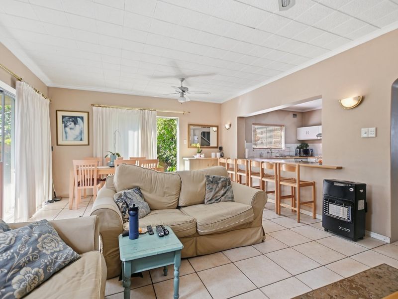 Open-plan living and dining area featuring tiled floors, a breakfast bar connecting to the kitchen, and direct access to the outdoor space.