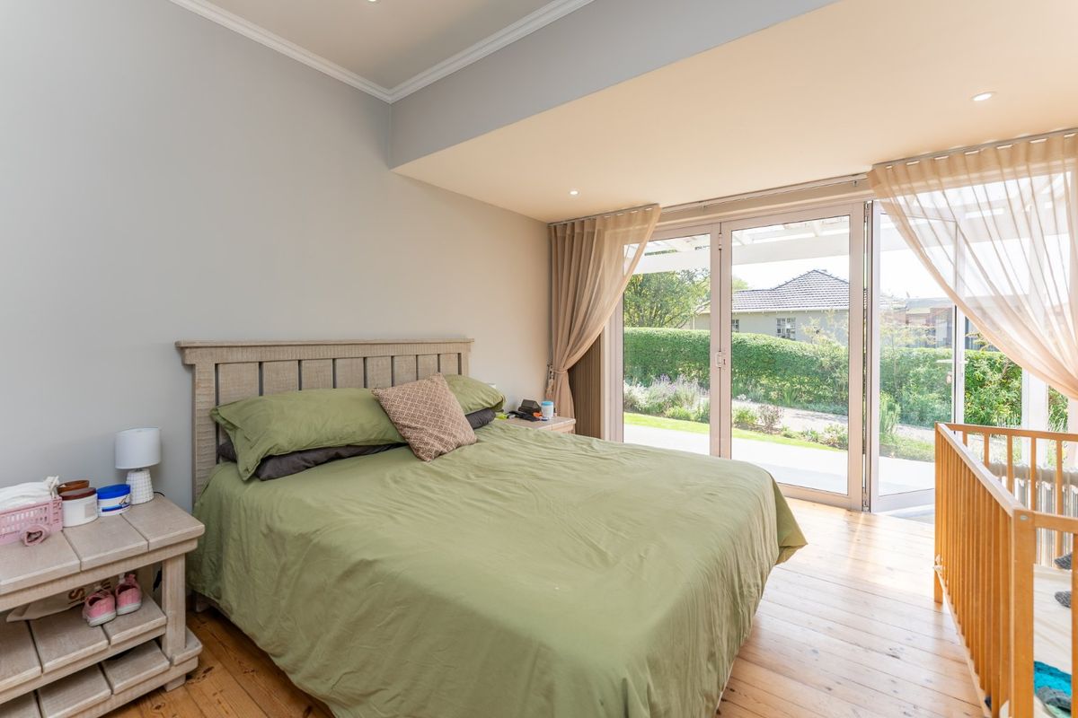 Spacious bedroom featuring hardwood flooring, recessed lighting, and large sliding glass doors providing direct access to the garden area.