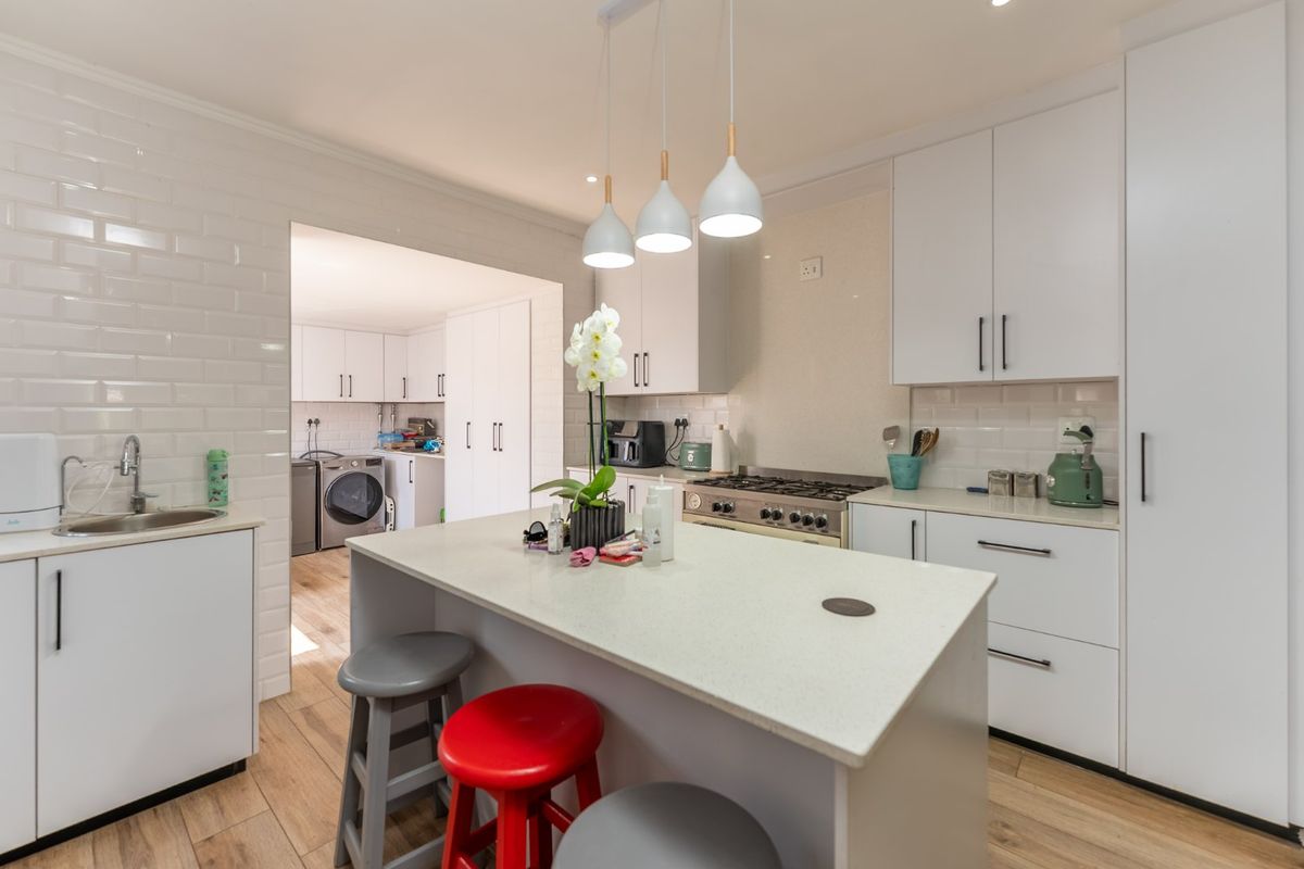 Modern kitchen featuring a central island with quartz countertops, gas cooktop, subway tile backsplash, and integrated cabinetry, with an adjacent scullery area.