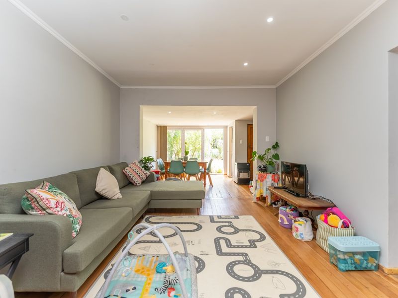 Open plan living and dining area featuring timber flooring, recessed lighting, and direct access to the rear garden through sliding glass doors.