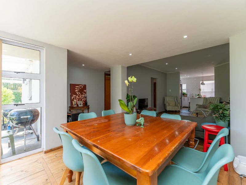 Open plan living and dining area featuring timber flooring, recessed downlighting, and direct access to an outdoor patio space.