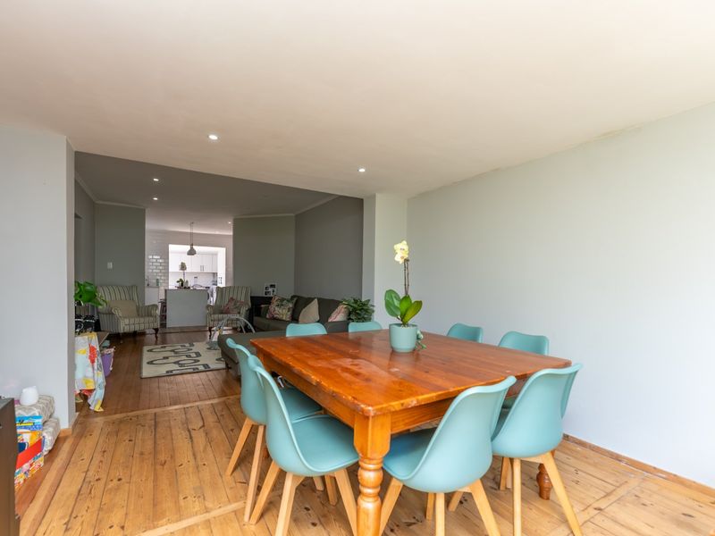 Open plan living and dining area featuring timber flooring and recessed lighting, flowing into a functional kitchen space.