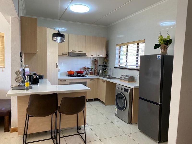 A functional kitchen featuring light wood cabinetry, a gas hob, breakfast nook, and tiled flooring, offering a clean and practical layout.