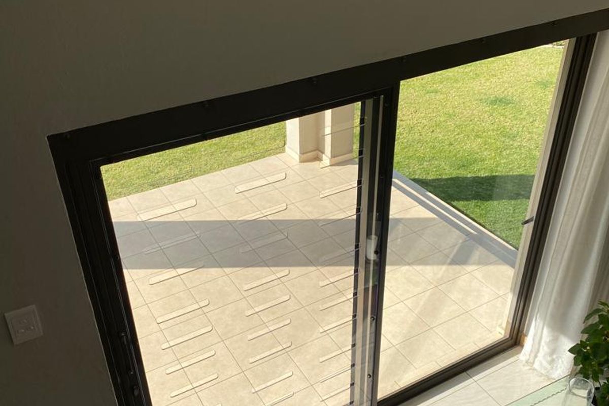 A view from an elevated position looking through a large sliding glass door onto a tiled patio and garden area.