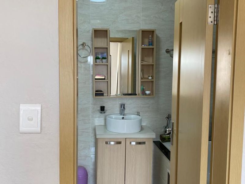 A functional bathroom featuring a modern vessel sink, vanity cabinet, wall-mounted mirror storage, and tiled finishes throughout.