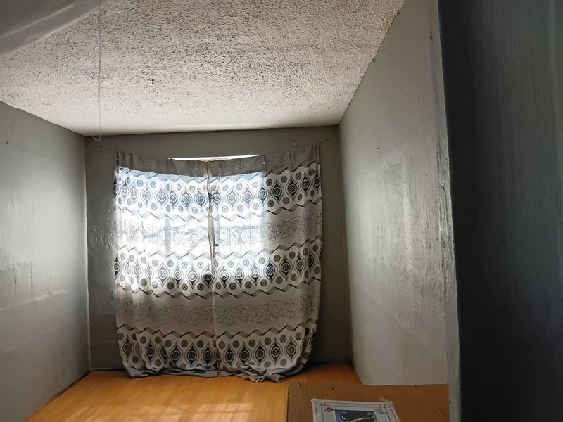 A vacant bedroom featuring laminate flooring and a textured popcorn ceiling, awaiting cosmetic updates to improve its overall aesthetic appeal.