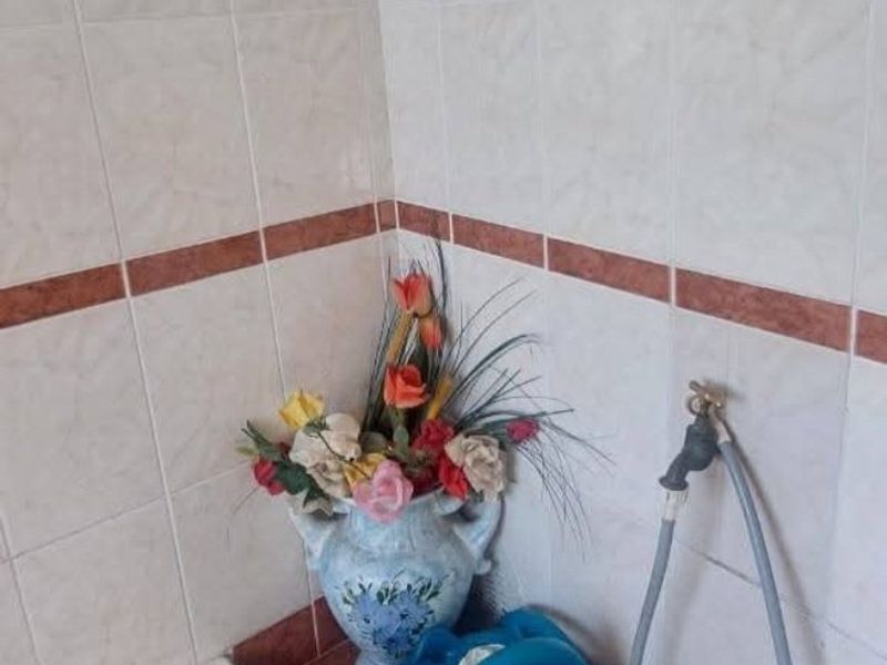 A corner view of a bathroom featuring a built-in bathtub and dated ceramic wall tiling with a decorative border.