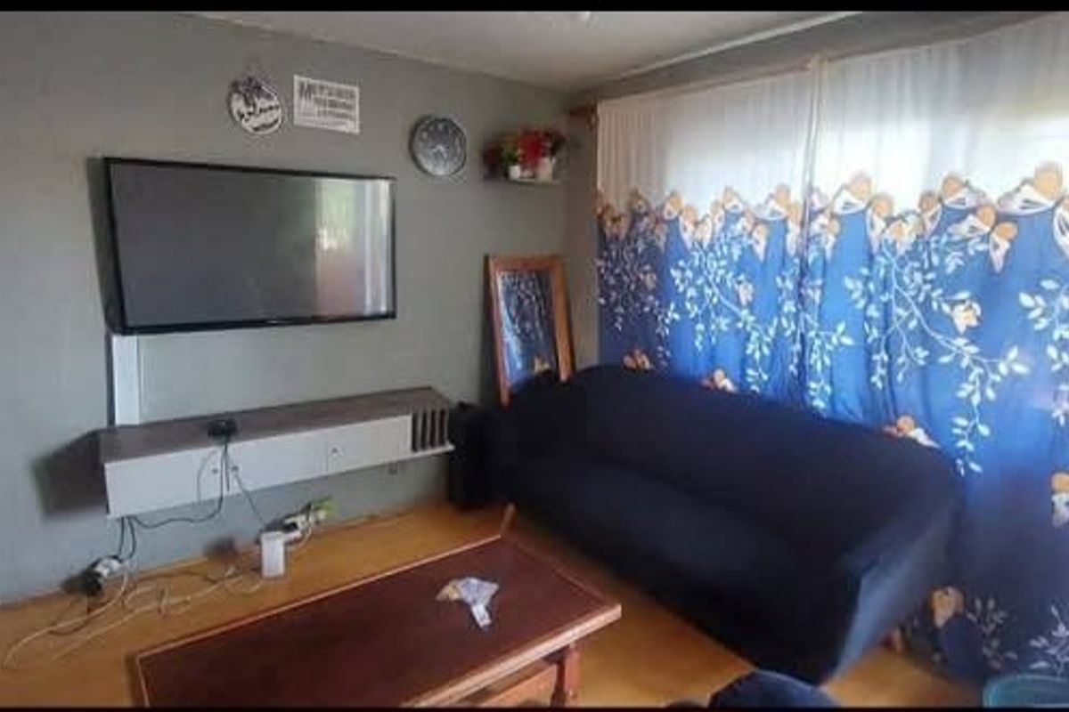 A living room featuring laminate flooring and a wall-mounted media console, providing a functional space for relaxation.