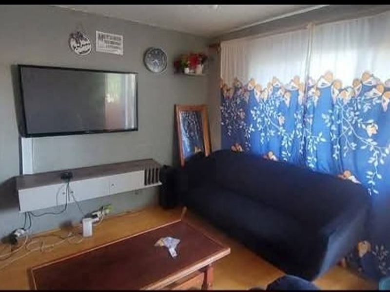 A living room featuring laminate flooring and a wall-mounted media console, providing a functional space for relaxation.