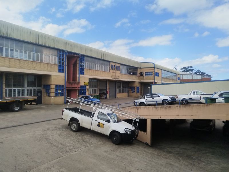 Industrial property exterior featuring a large warehouse facade, concrete driveway, and an elevated ramp for vehicle access.