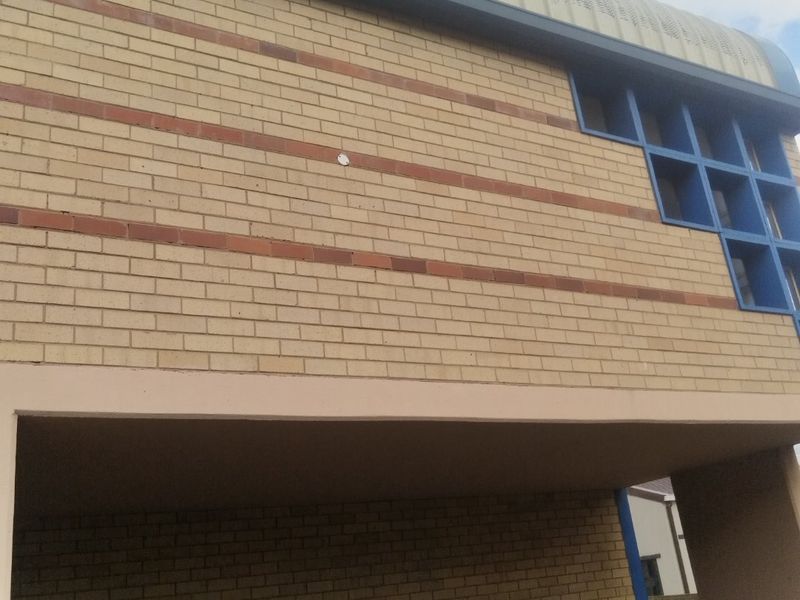 Front elevation of an industrial property featuring a distinctive curved metal roof, brick facade, and a secure roller shutter door.