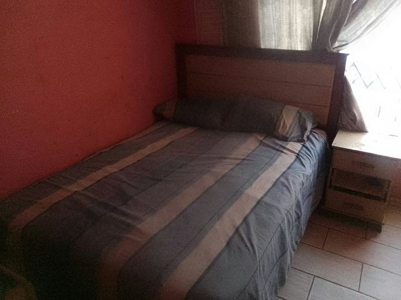 A bedroom featuring tiled flooring and a red accent wall, requiring cosmetic updates to improve the overall aesthetic.