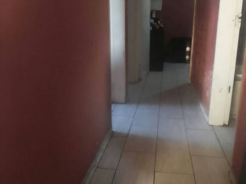 A narrow interior hallway featuring tiled flooring and painted walls, providing access to adjacent rooms.