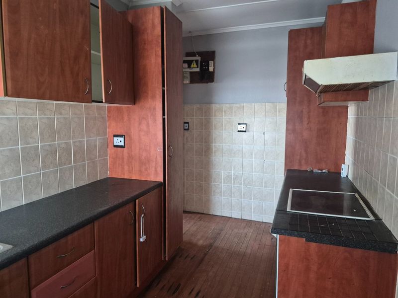 A functional kitchen featuring laminate cabinetry, tiled splashbacks, and a built-in electric hob with an extractor fan.
