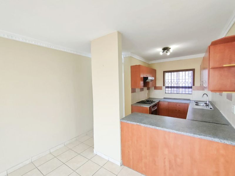 A functional kitchen featuring built-in cabinetry, laminate countertops, a built-in hob and oven, and tiled flooring, offering a clean and practical layout.