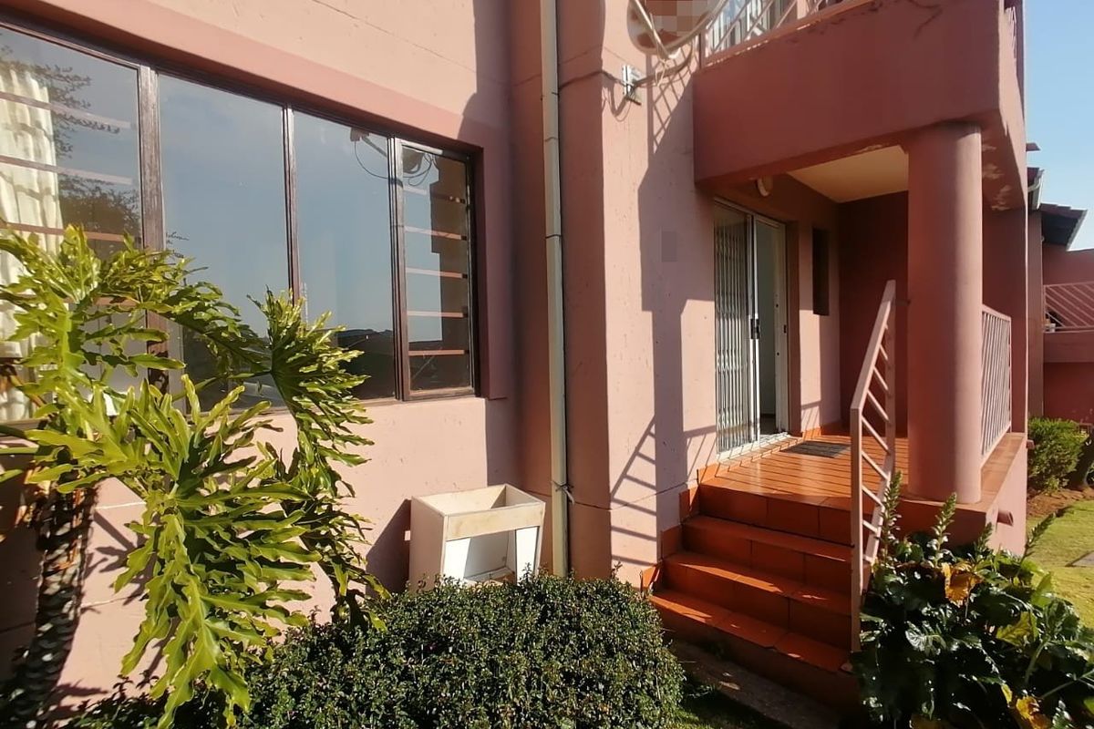 Rear exterior view of the townhouse featuring a tiled staircase, metal balustrade, and sliding door access to the living area.