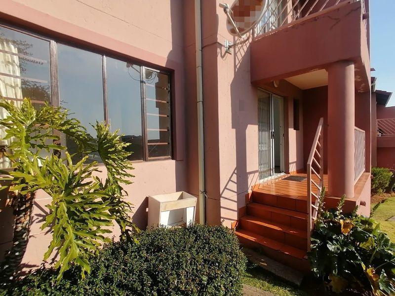 Rear exterior view of the townhouse featuring a tiled staircase, metal balustrade, and sliding door access to the living area.