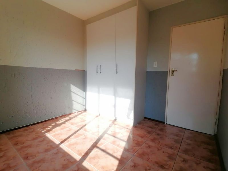 A vacant bedroom featuring tiled flooring and built-in cupboards, offering a neutral canvas for personalization.