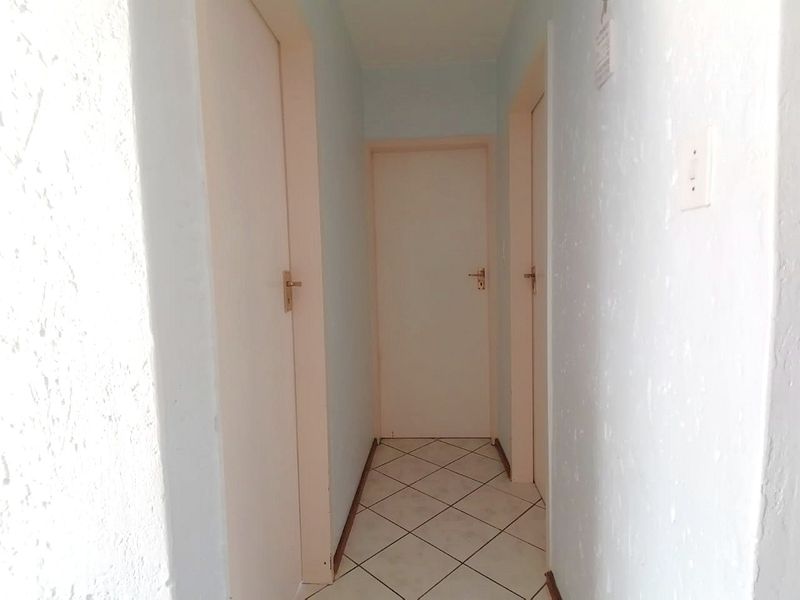 A functional hallway featuring tiled flooring and multiple internal doors, providing access to various rooms within the townhouse.