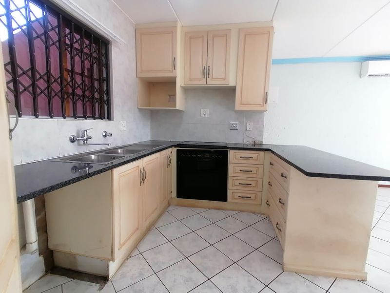 Functional kitchen featuring granite countertops, built-in cabinetry, integrated oven, and tiled flooring, offering a practical layout ready for cosmetic updates.