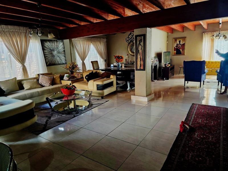 Spacious open-plan living and dining area featuring high exposed timber beam ceilings and large tiled flooring throughout.
