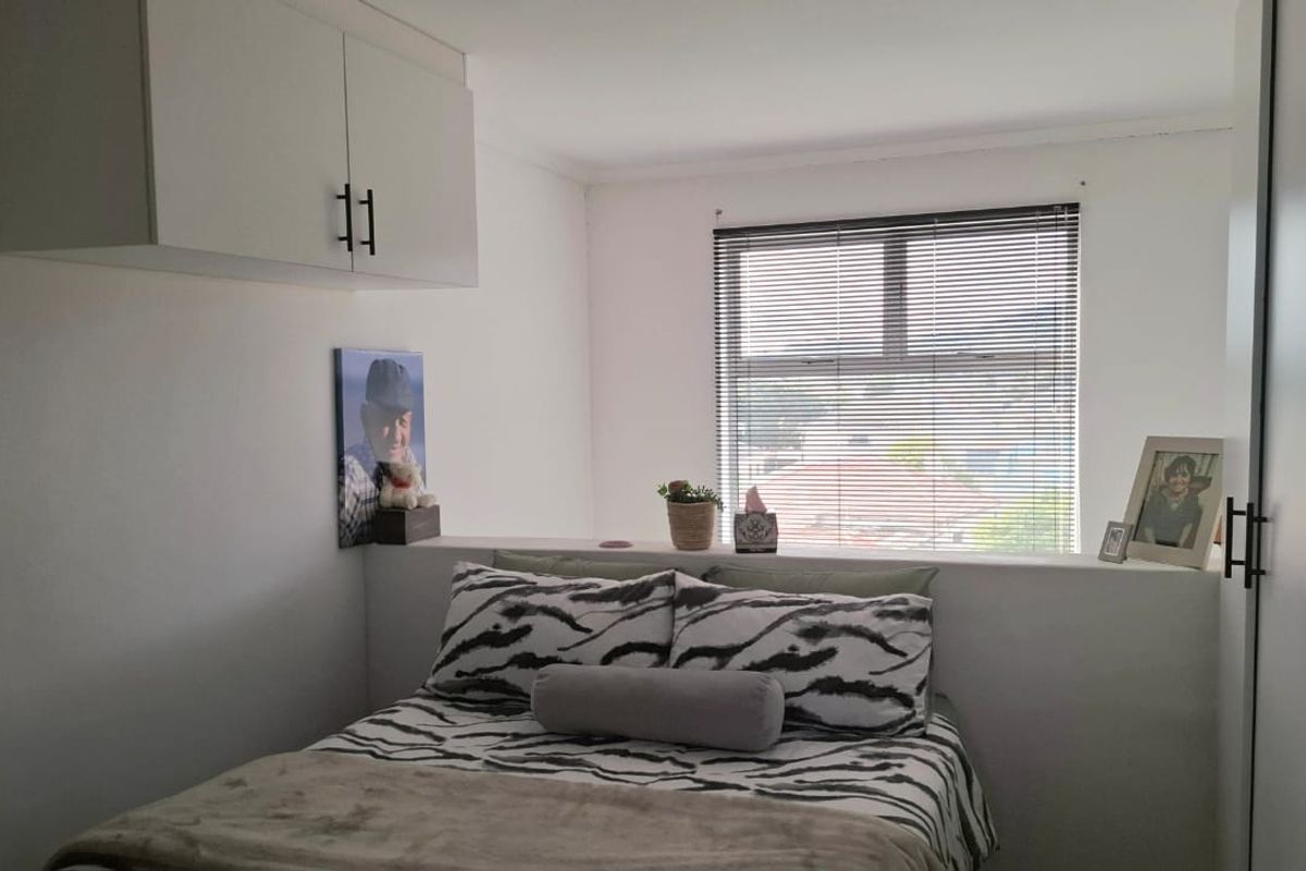 A bedroom featuring built-in cabinetry, a built-in wardrobe, and venetian blinds, providing a functional and compact living space.