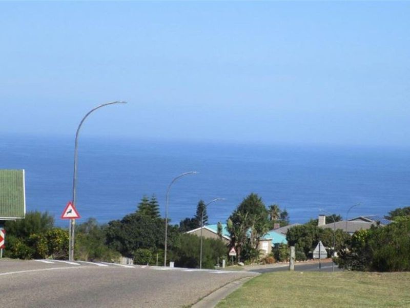 A street-level view of the neighbourhood approach, featuring asphalt roads, street lighting, and a clear view of the ocean in the distance.