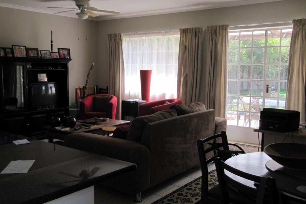 Open plan living and dining area featuring tiled flooring, a ceiling fan, and direct access to the rear patio through glass french doors.