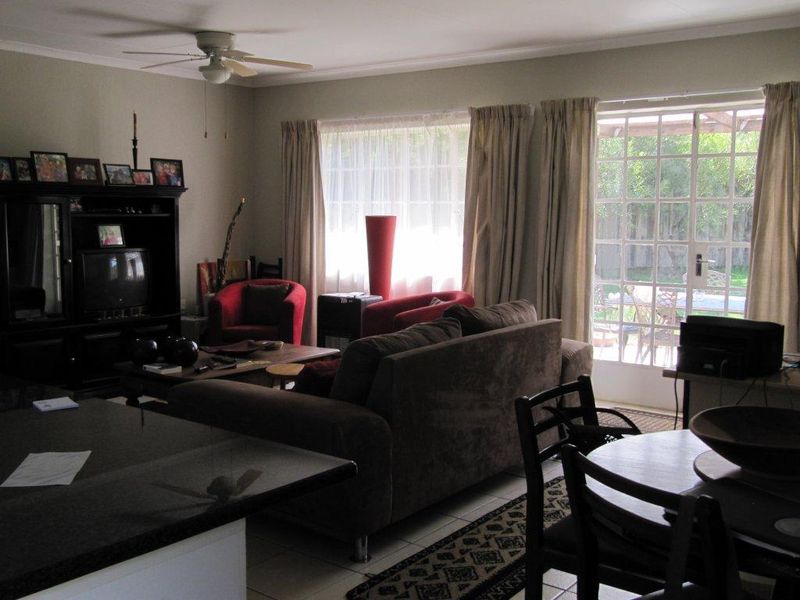 Open plan living and dining area featuring tiled flooring, a ceiling fan, and direct access to the rear patio through glass french doors.