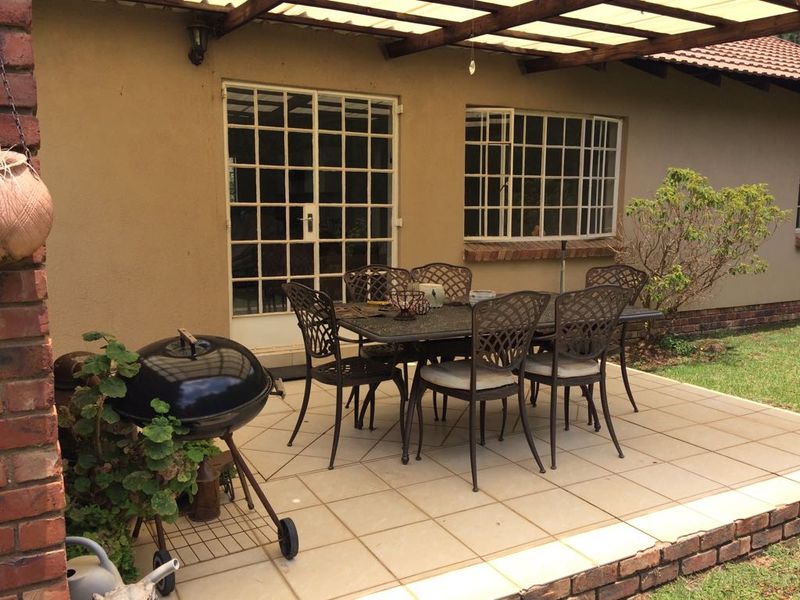 Covered outdoor patio area featuring tiled flooring, a timber pergola structure, and direct access to the home through a security gate.
