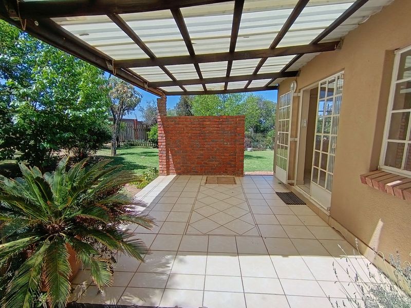 A covered outdoor patio area featuring tiled flooring, a brick privacy wall, and direct access to the home through french doors.