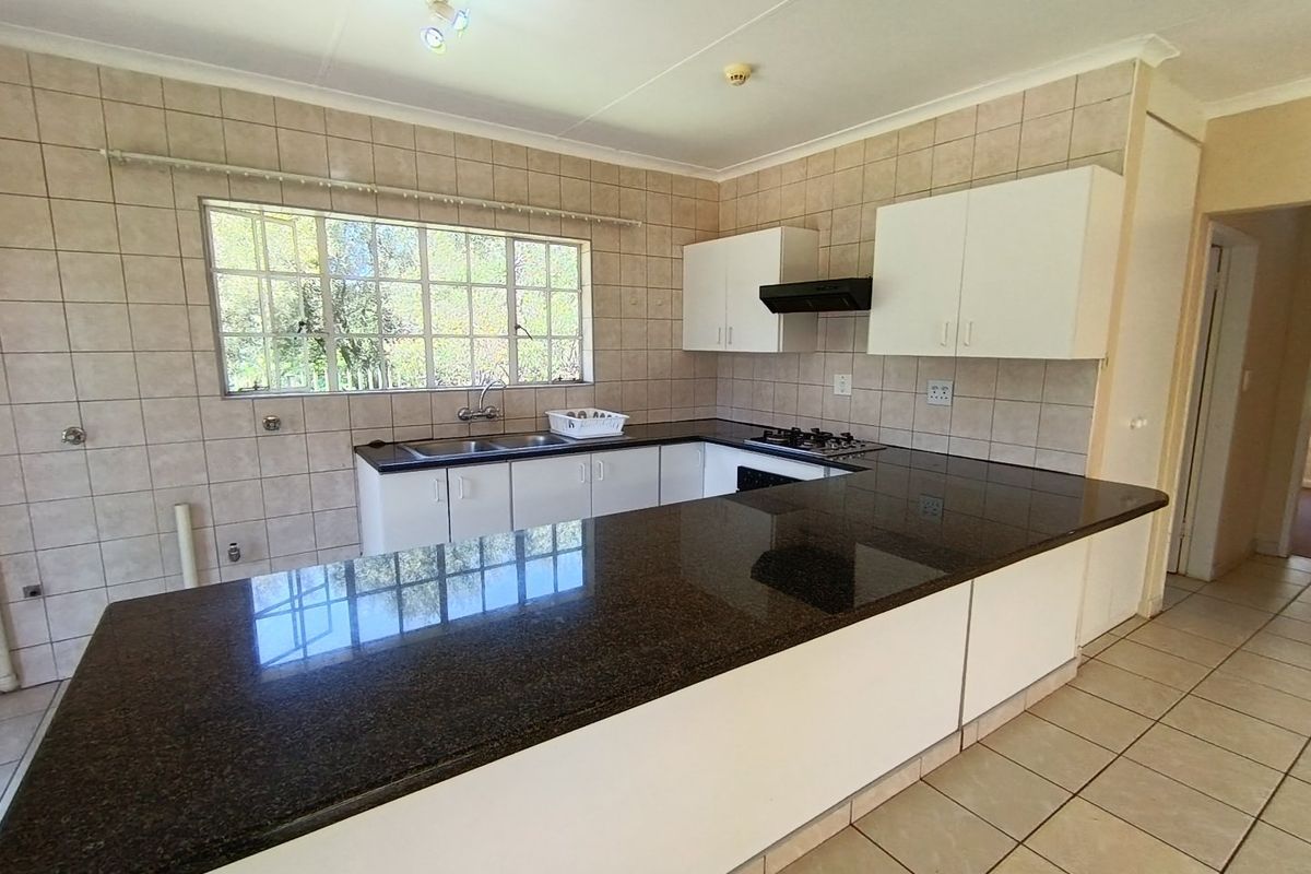 A functional kitchen featuring granite countertops, a built-in gas hob with extractor fan, and ample cabinetry, offering a clean and practical workspace.