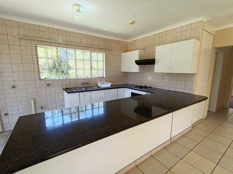 A functional kitchen featuring granite countertops, a built-in gas hob with extractor fan, and ample cabinetry, offering a clean and practical workspace.
